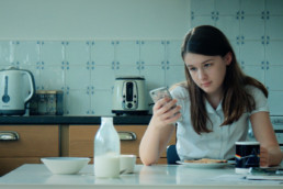 Girl with iPhone at breakfast table